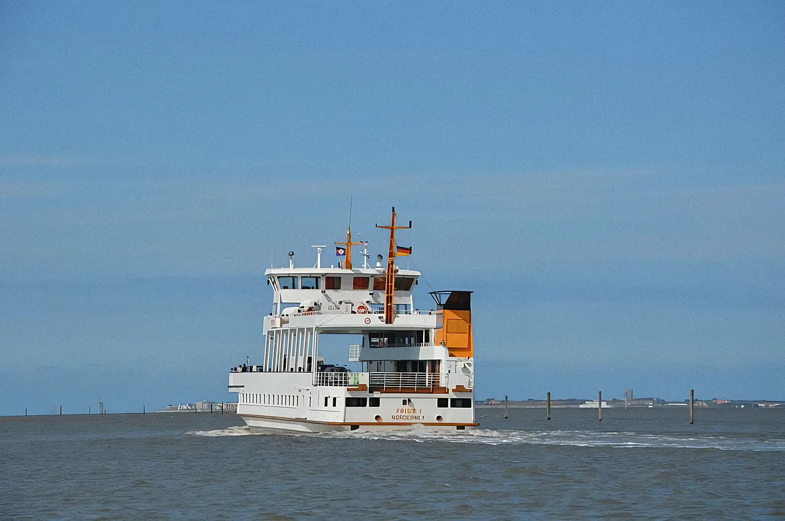Weiße Fähre mit orangefarbenem Schornstein fährt auf dem Meer, blauer Himmel, Norden-Nordsee-Fähre.